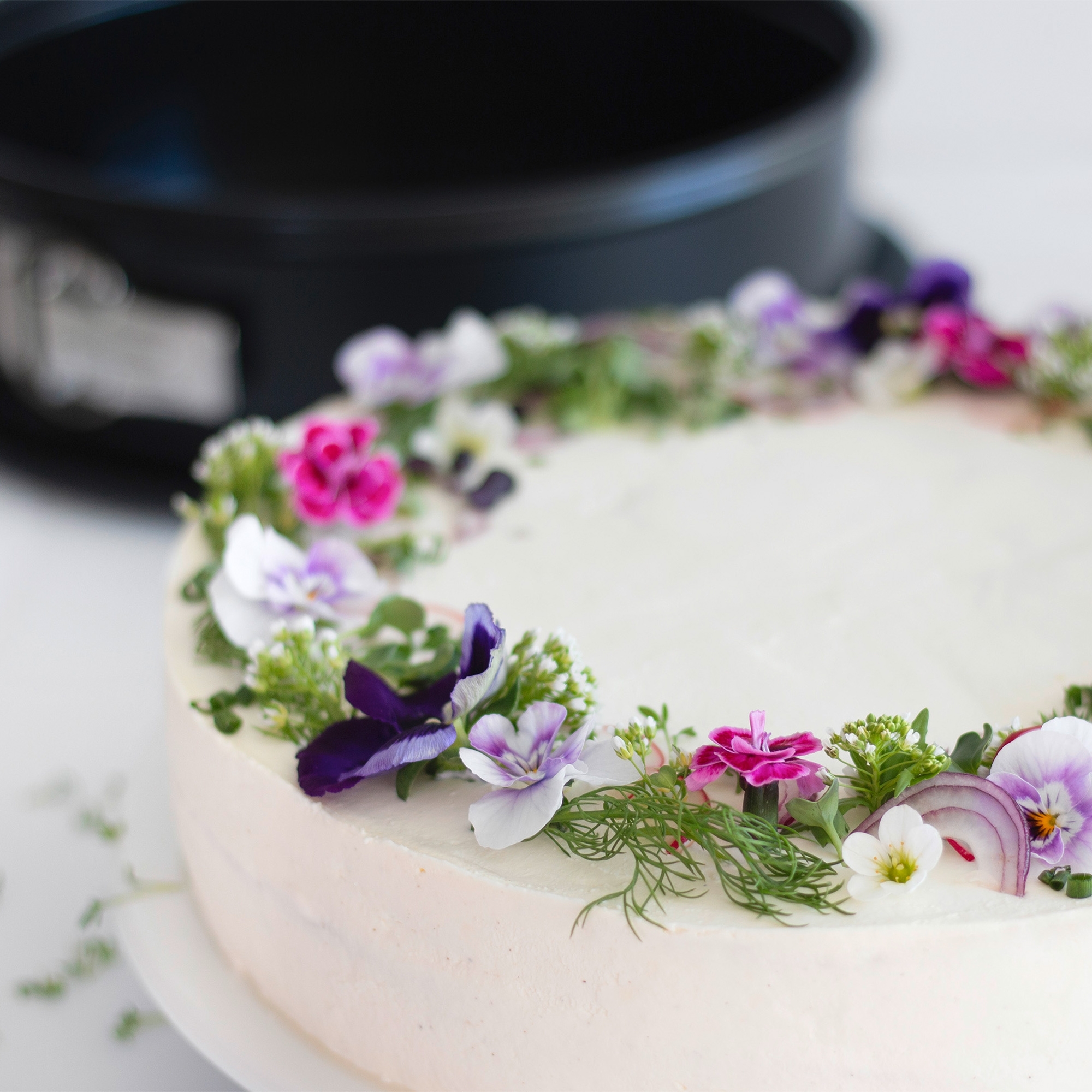 Runde Sahnetorte mit bunten essbaren Blüten