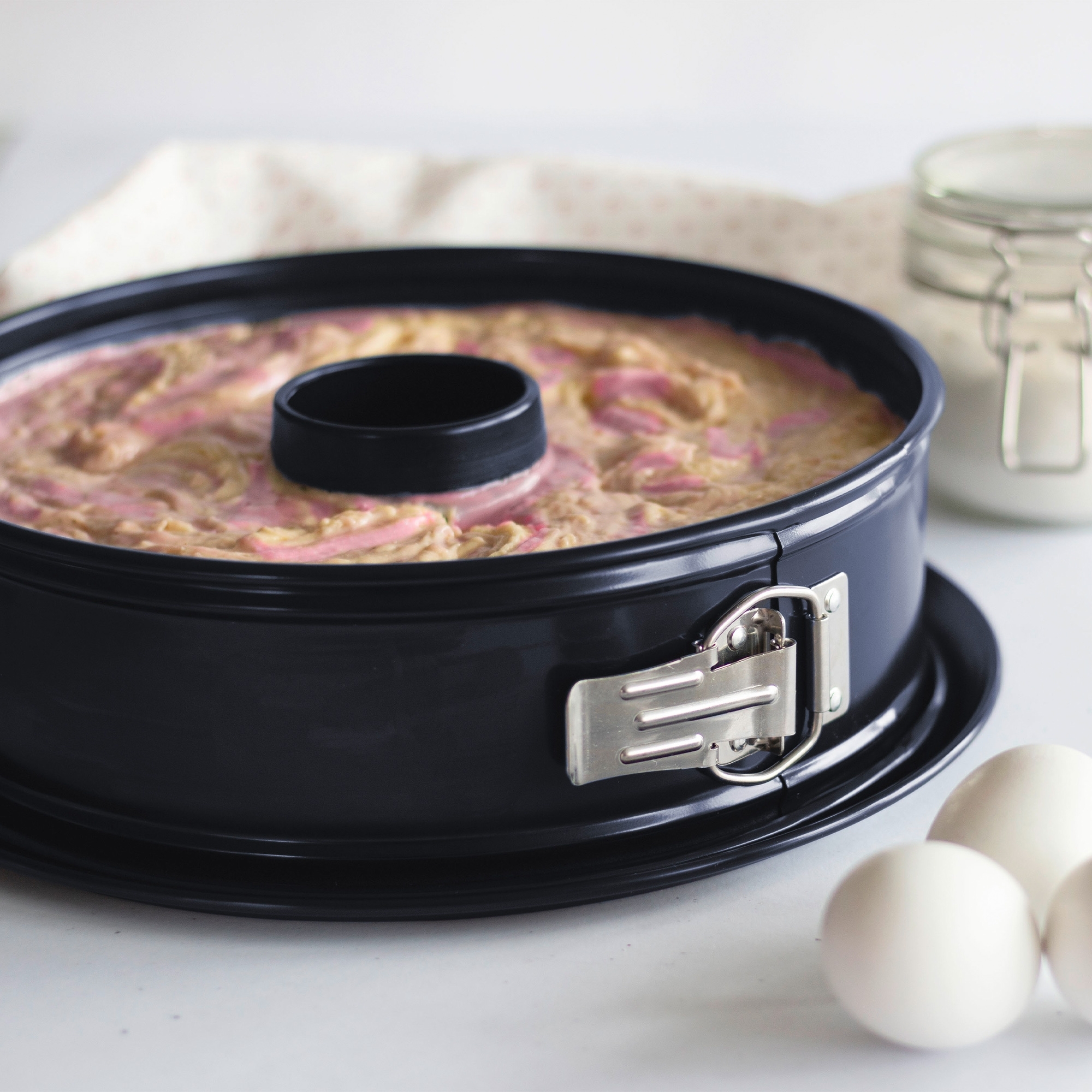 Schwarze Springform mit Teig und Rohrboden