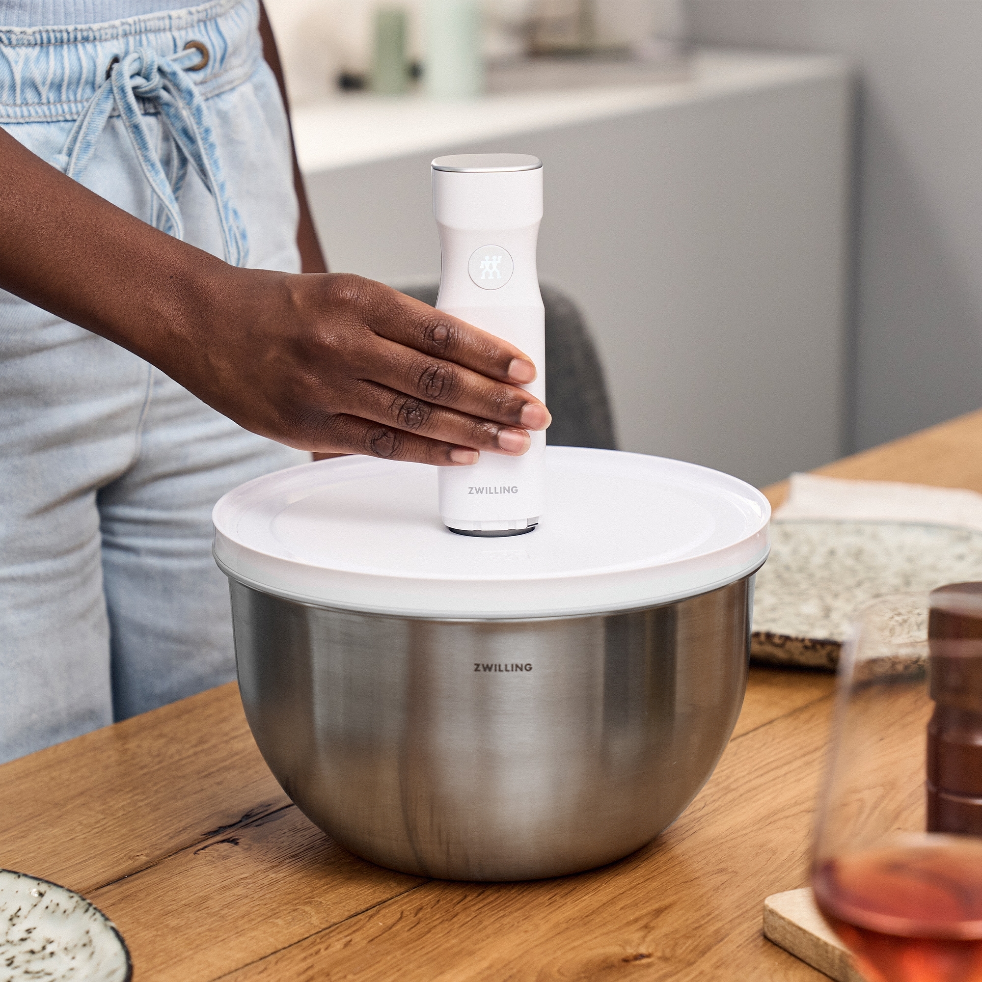 Person benutzt weißen Zwilling Vakuumdeckel auf Schüssel