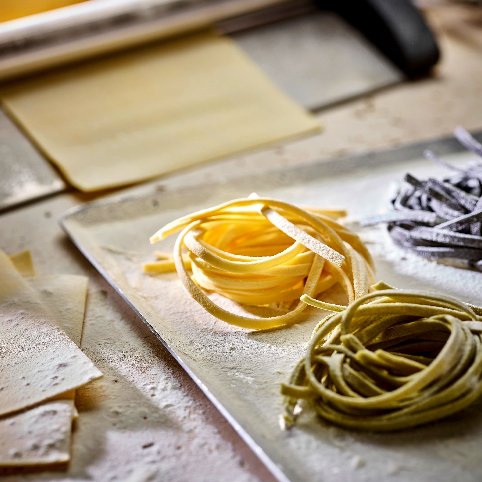 Assorted fresh tagliatelle nests on floured board