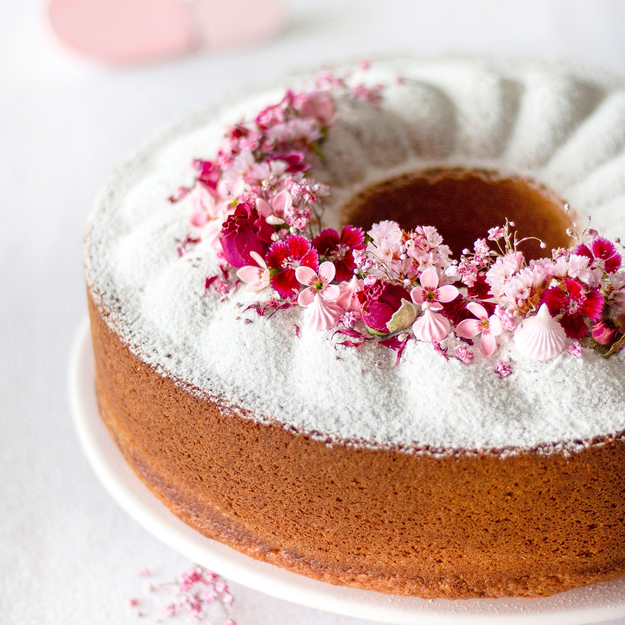 Runder Gugelhupf mit Zucker und rosa Blüten